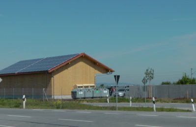 Holzhaus mit Recyclingcontainer davor
