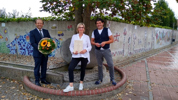 Gruppenfoto mit langjähriger Mitarbeiterin in der Mitte mit Urkunde in der Hand