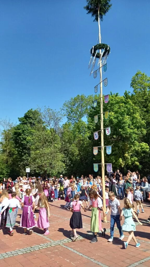 Kinder tanzen um den Maibaum