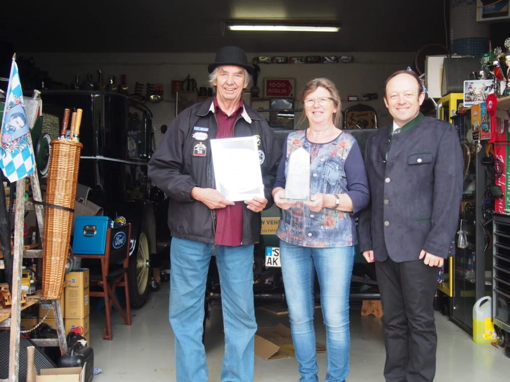 3 Personen vor einem Oldtimer