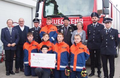 Foto FFW-Jugend-Aholfing.jpg: Die Familie Kandler übergab einen Spendenscheck in Höhe von 500 Euro für die Aholfinger Jugendfeuerwehr: Alfred Kandler (4. von rechts) , Rosemarie Kandler (3. von rechts), Joschua Seidel (1. Reihe mit Scheck) und die Führungsriege der Feuerwehr mit Ehrengästen