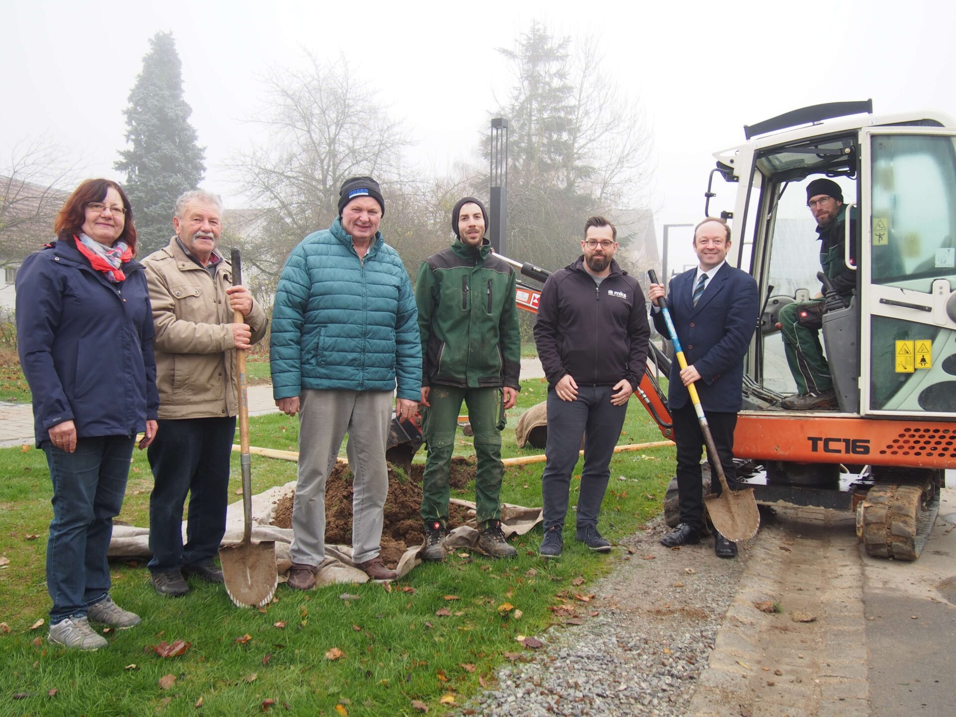 Bauingenieur Rainer Bachmann (3. v. re.) mit den Verantwortlichen des Paitzkofner Dorferneuerungsarbeitskreises und den Vertretern der beteiligten Firma beim der Pflanzung des letzten Strauchs in der Paitzkofner Ortsmitte: von links: Kirchenpflegerin und Gartenbauvereinsvorsitzende Brigitte Kiendl, Arbeitskreisvorsitzender Norbert Kiendl, Erwin Weinzierl, Lorenz Hackl (Fa. Pohl & Schneider) , Rainer Bachmeier (Büro MKS, Ascha), Bürgermeister Christian Hirtreiter und Thomas Sebald ((im Kleinbagger) vom Landschaftsgartenbaubetrieb „Pohl & Schneider“)