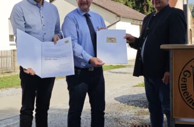 3 Personen bei Urkundenübergabe