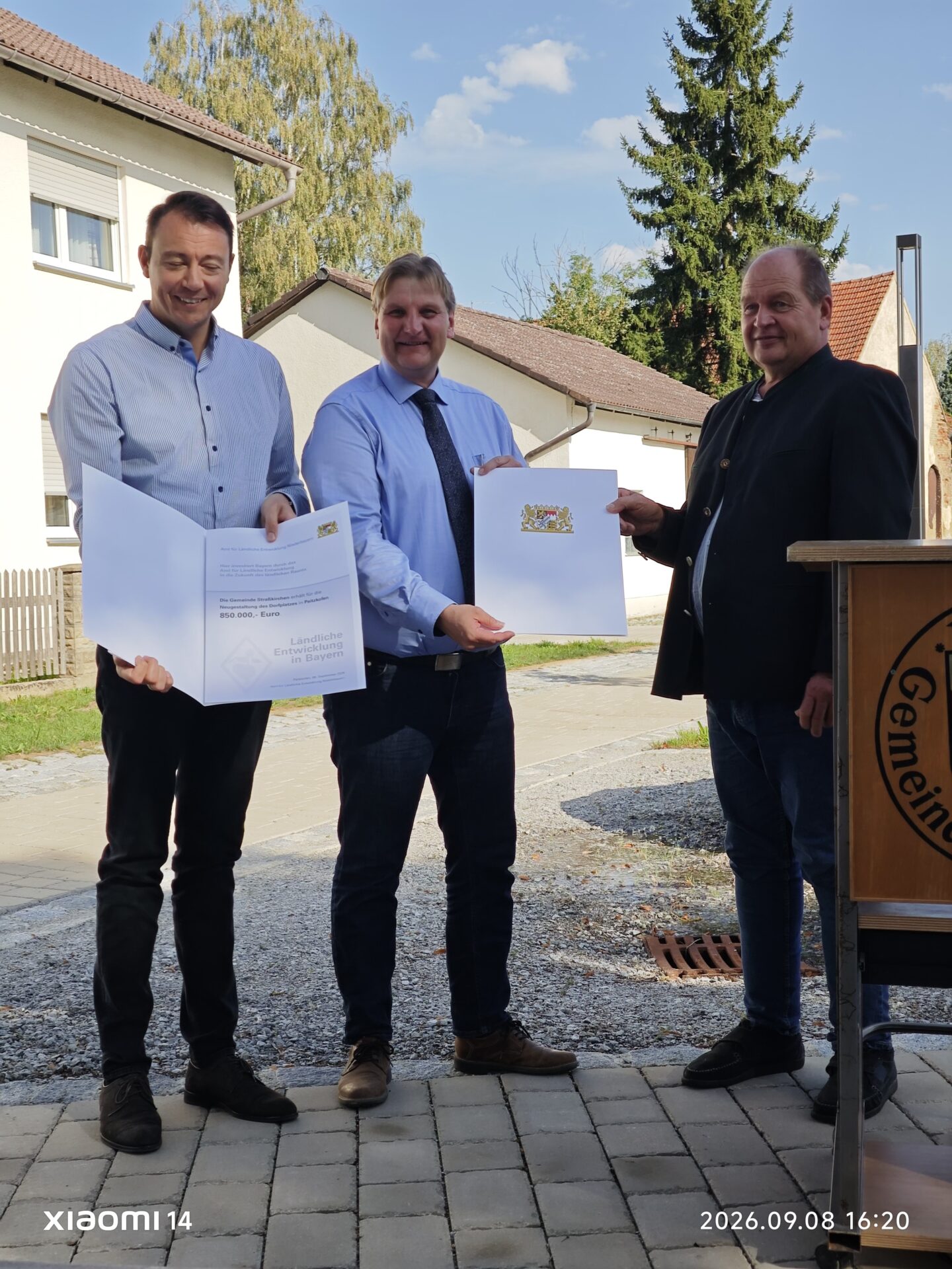 3 Personen bei Urkundenübergabe