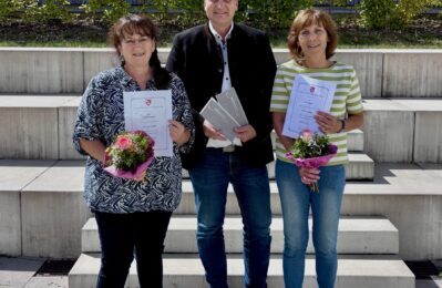 3 Personen bei Urkundenübergabe